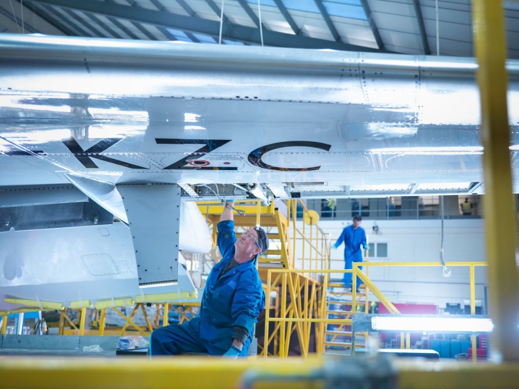 Engineer working on aircraft wing in aircraft maintenance factory